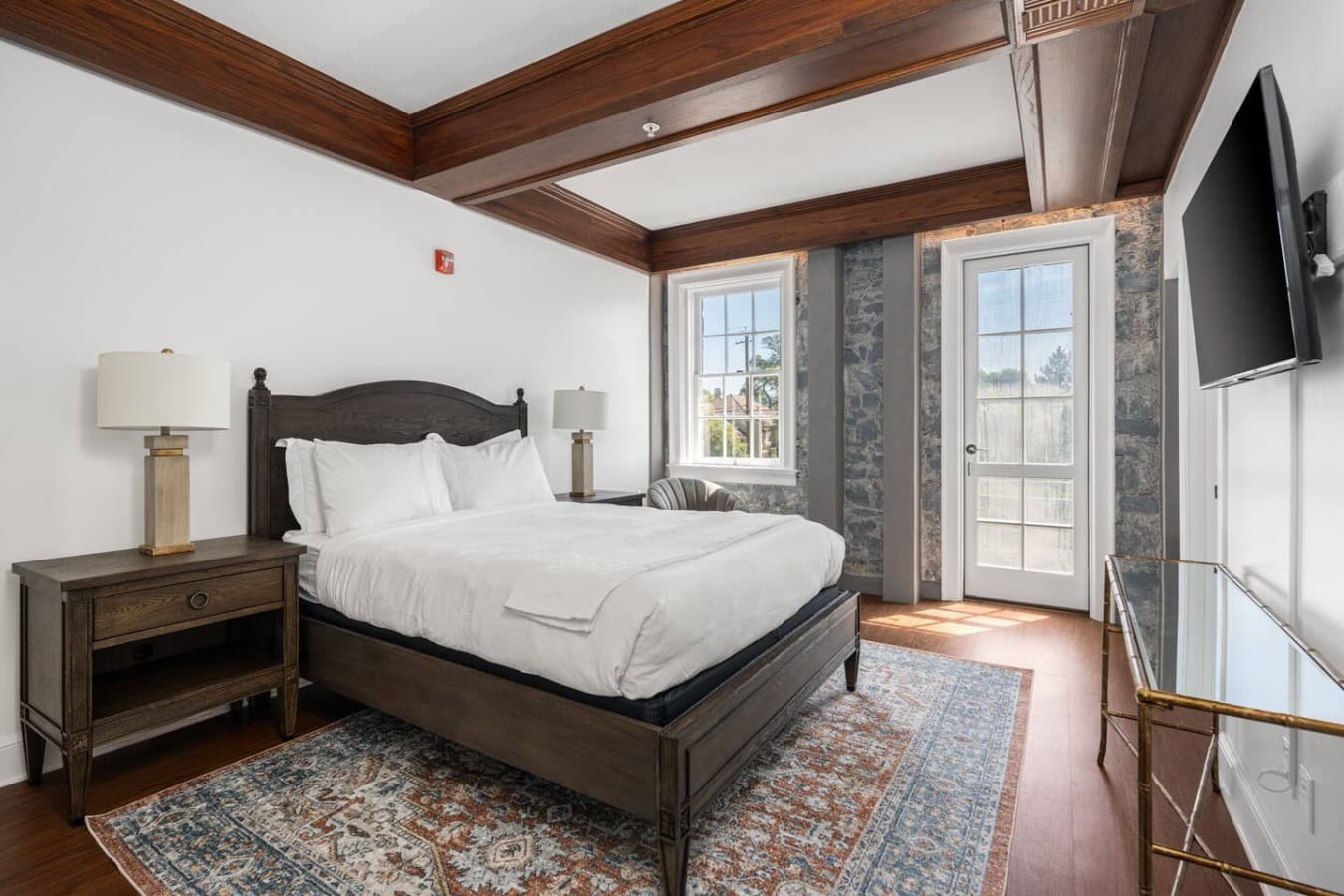 This is the private room you will be renting showcasing warm wood details, a cozy bed, and direct access to the outdoor balcony doors.