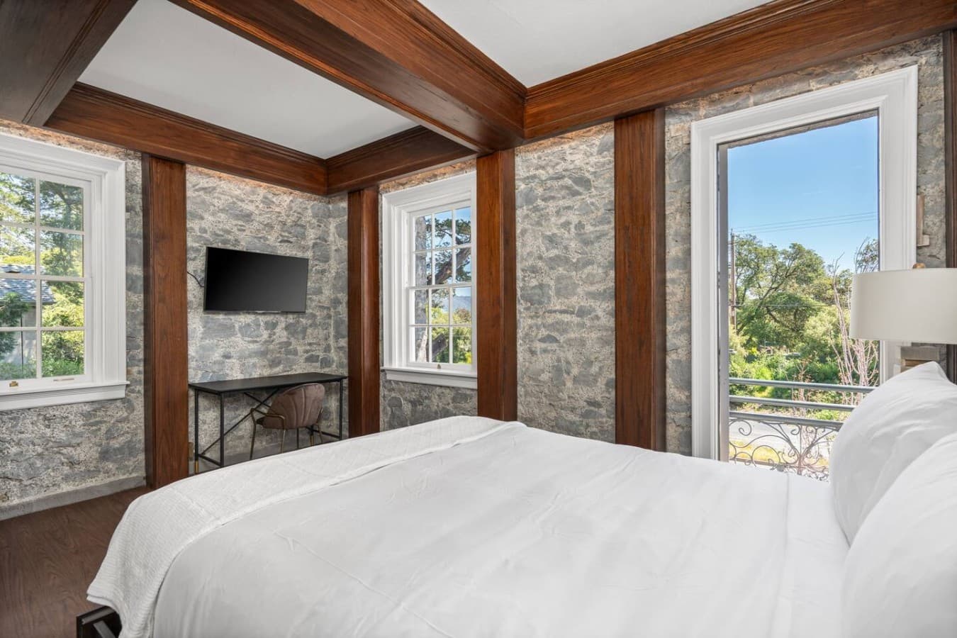 This is the private room you will be renting featuring warm wood-beam ceilings, stone-accented walls, and a cozy bed.