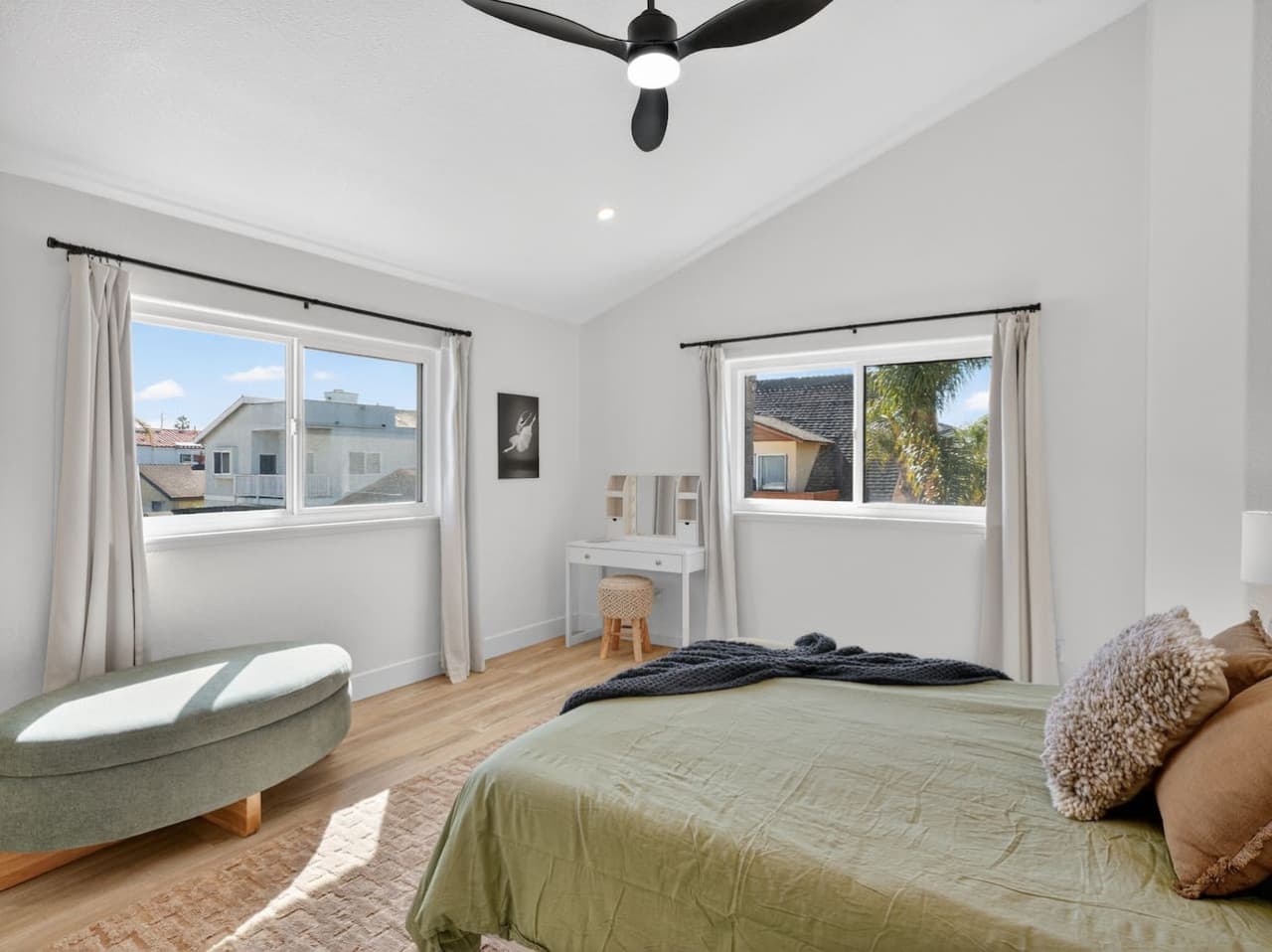 Bright bedroom with large windows and comfortable furnishings.