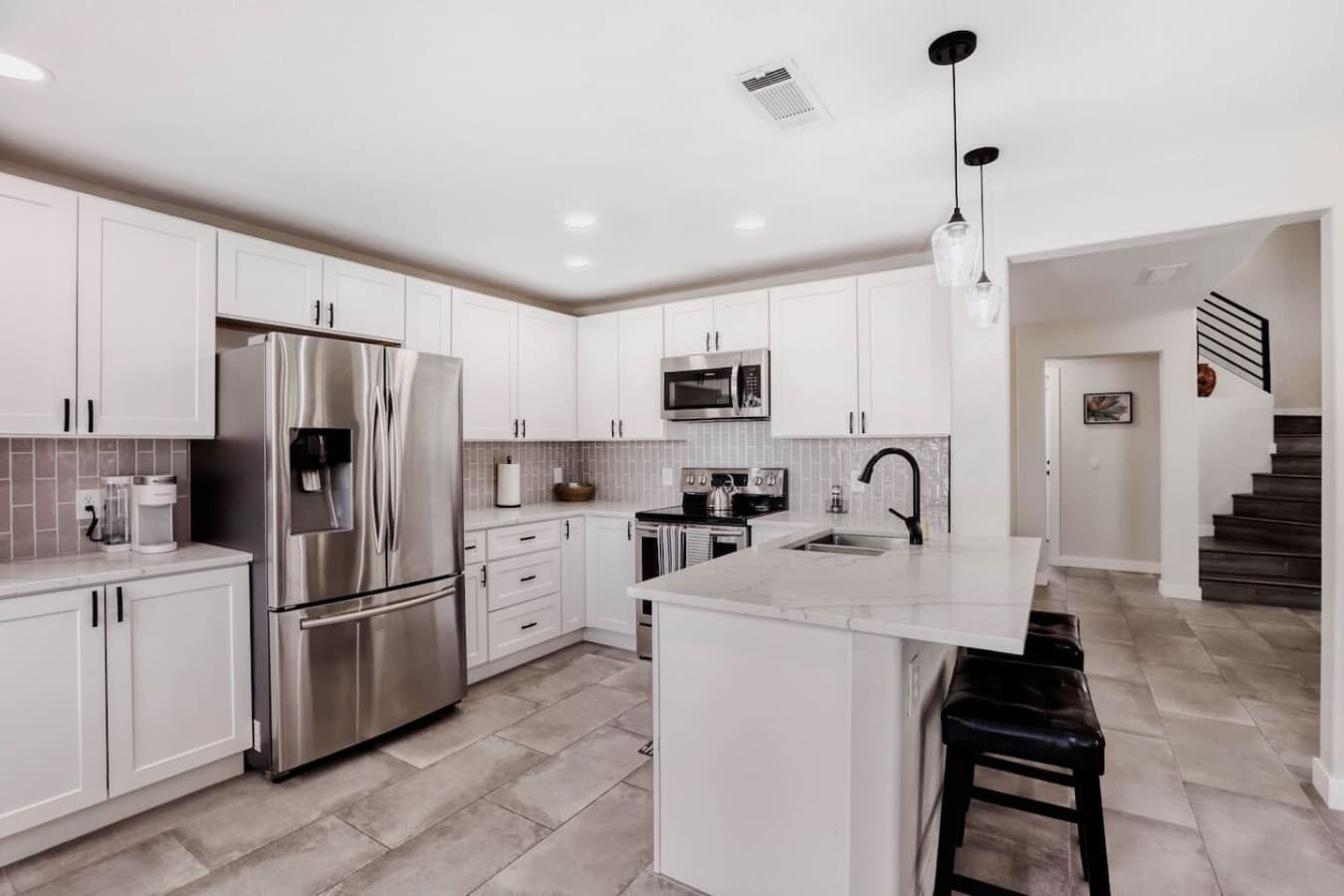 Sleek white kitchen with stainless steel appliances and generous counter space.