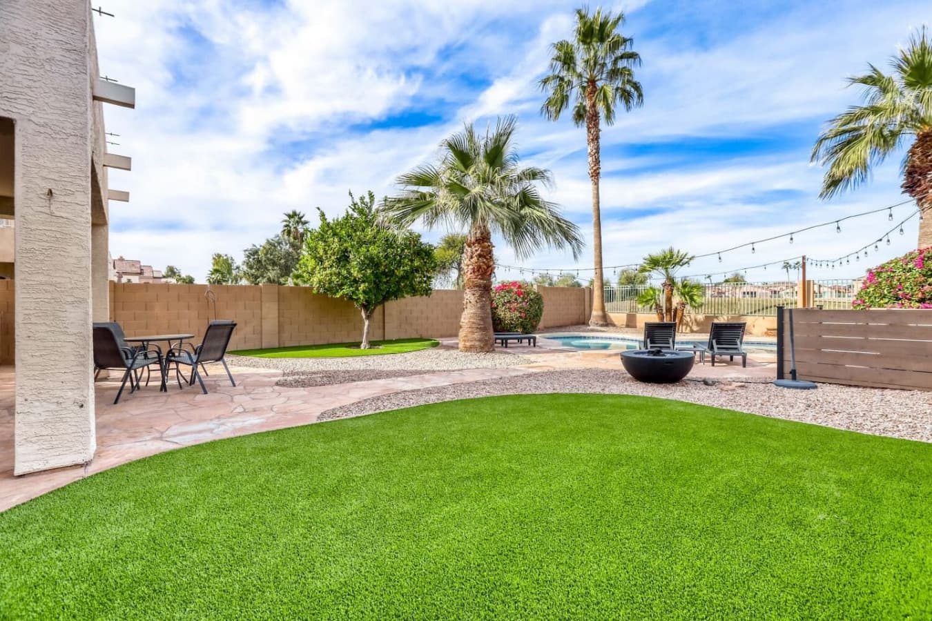 Expansive grassy yard surrounded by palm trees and space to relax or play.