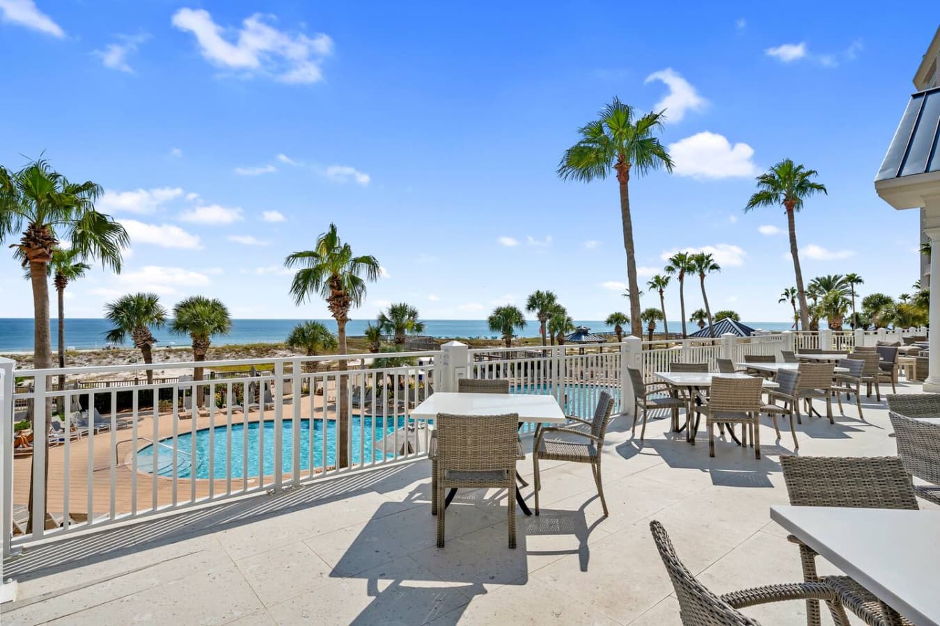 Outdoor seating area overlooking the pool and palm lined views.