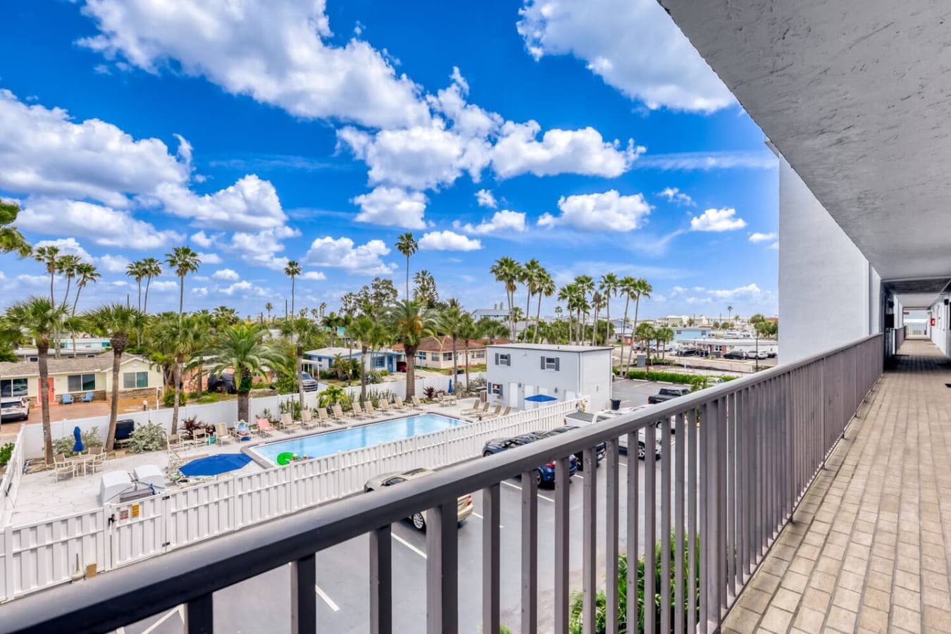 Balcony overlooking pool area and palm tree views.