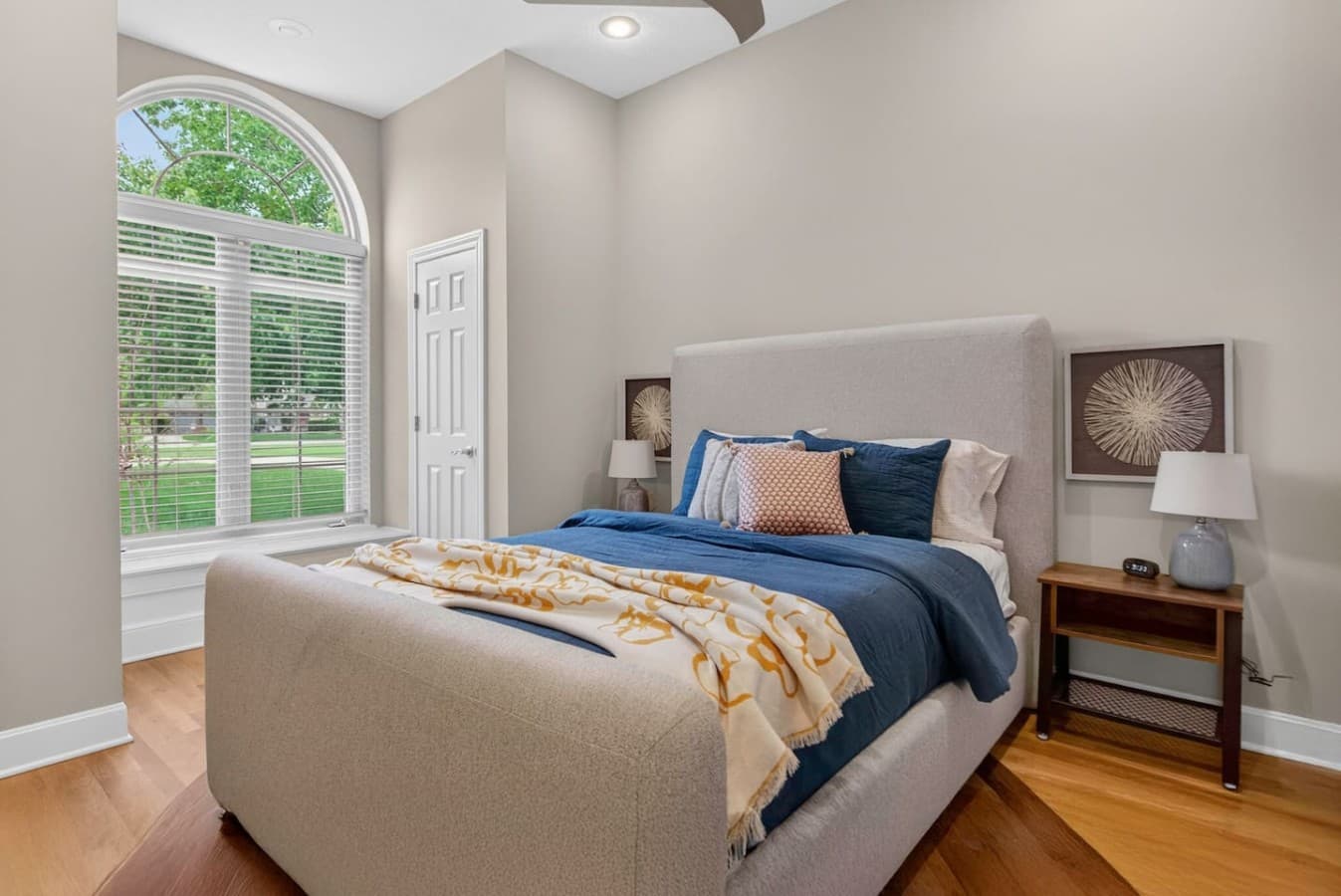 Bright and cozy bedroom with vaulted ceilings, large arched windows, and peaceful natural light throughout the space.