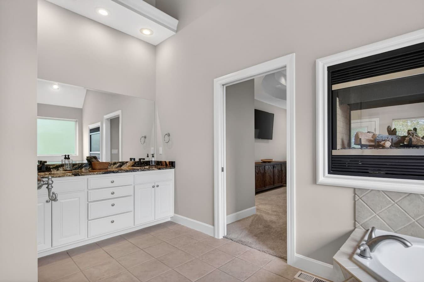 Elegant ensuite bathroom featuring expansive mirrors, generous storage, and an open airy design.