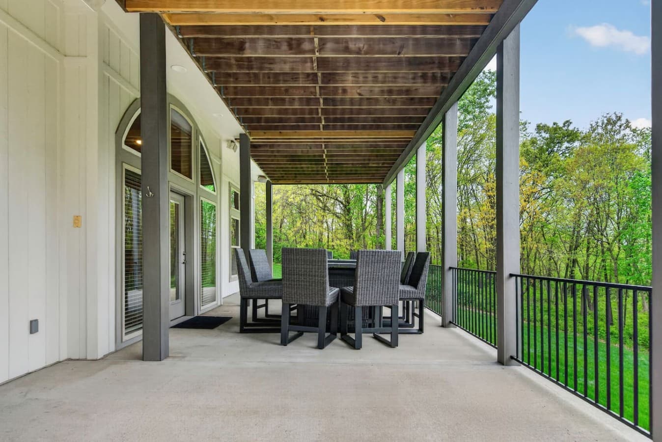 Expansive covered deck with outdoor dining space and peaceful wooded surroundings.