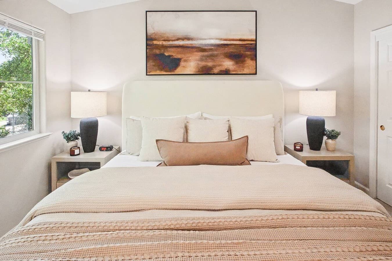 Spacious primary bedroom with soft neutral tones and a cozy hotel style feel.