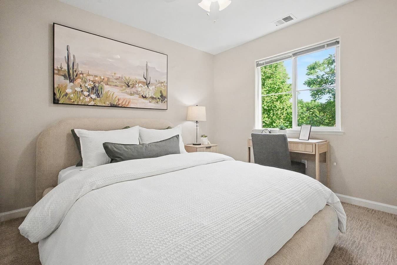 Cozy bedroom retreat with bright windows and a dedicated workspace area.