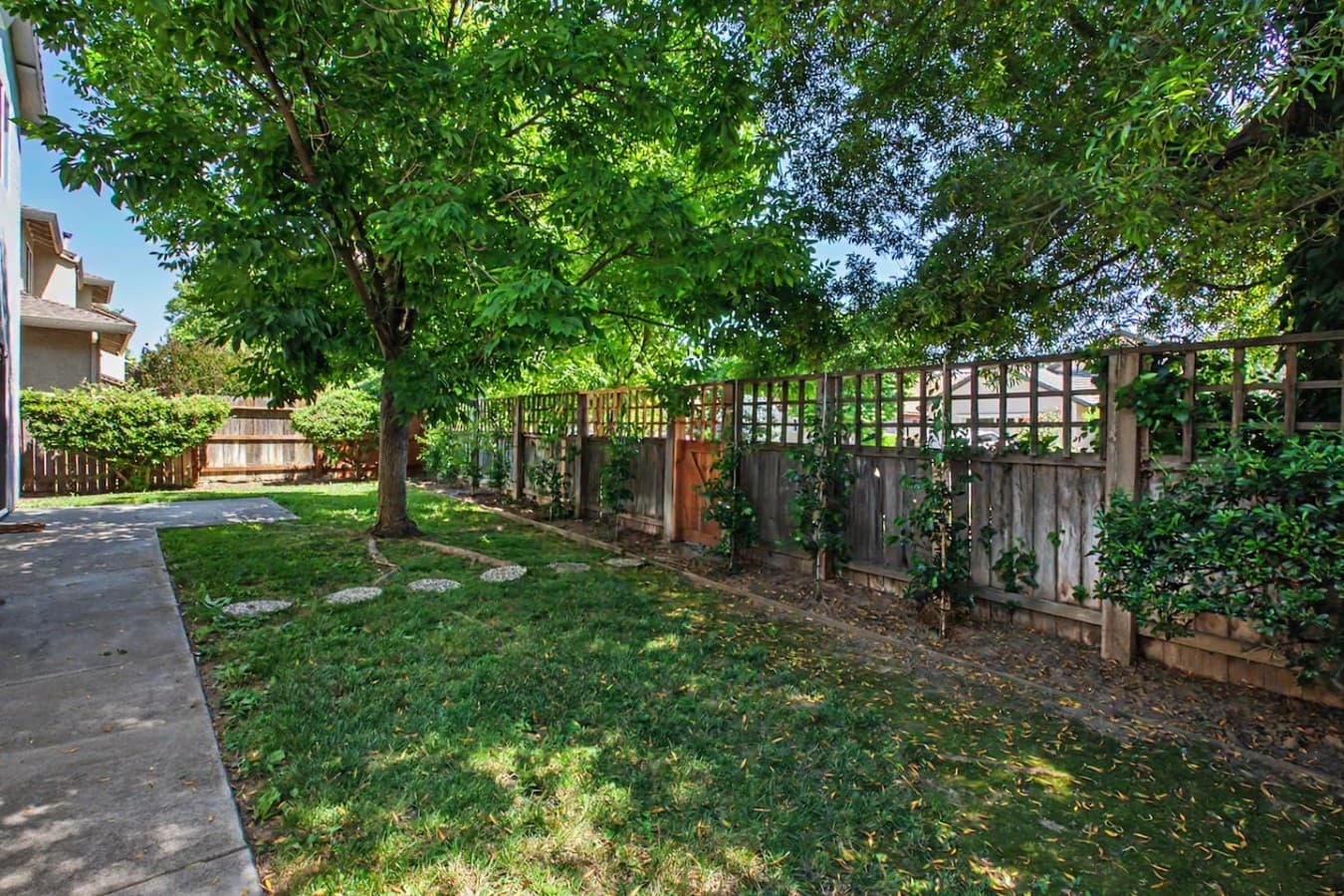 Spacious grassy yard surrounded by greenery and fencing for added privacy.