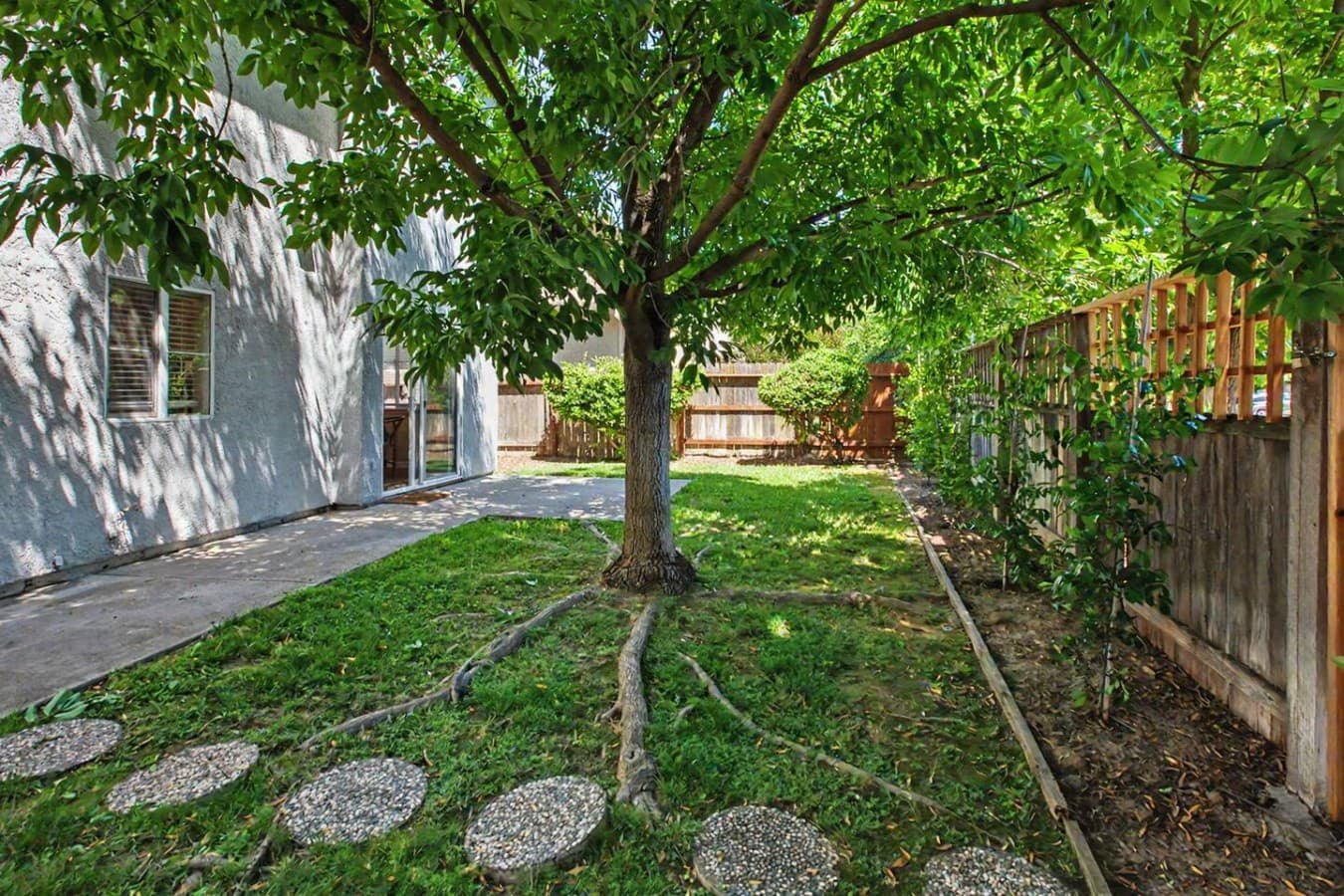 Private backyard with mature trees, shaded seating areas, and a peaceful outdoor setting.