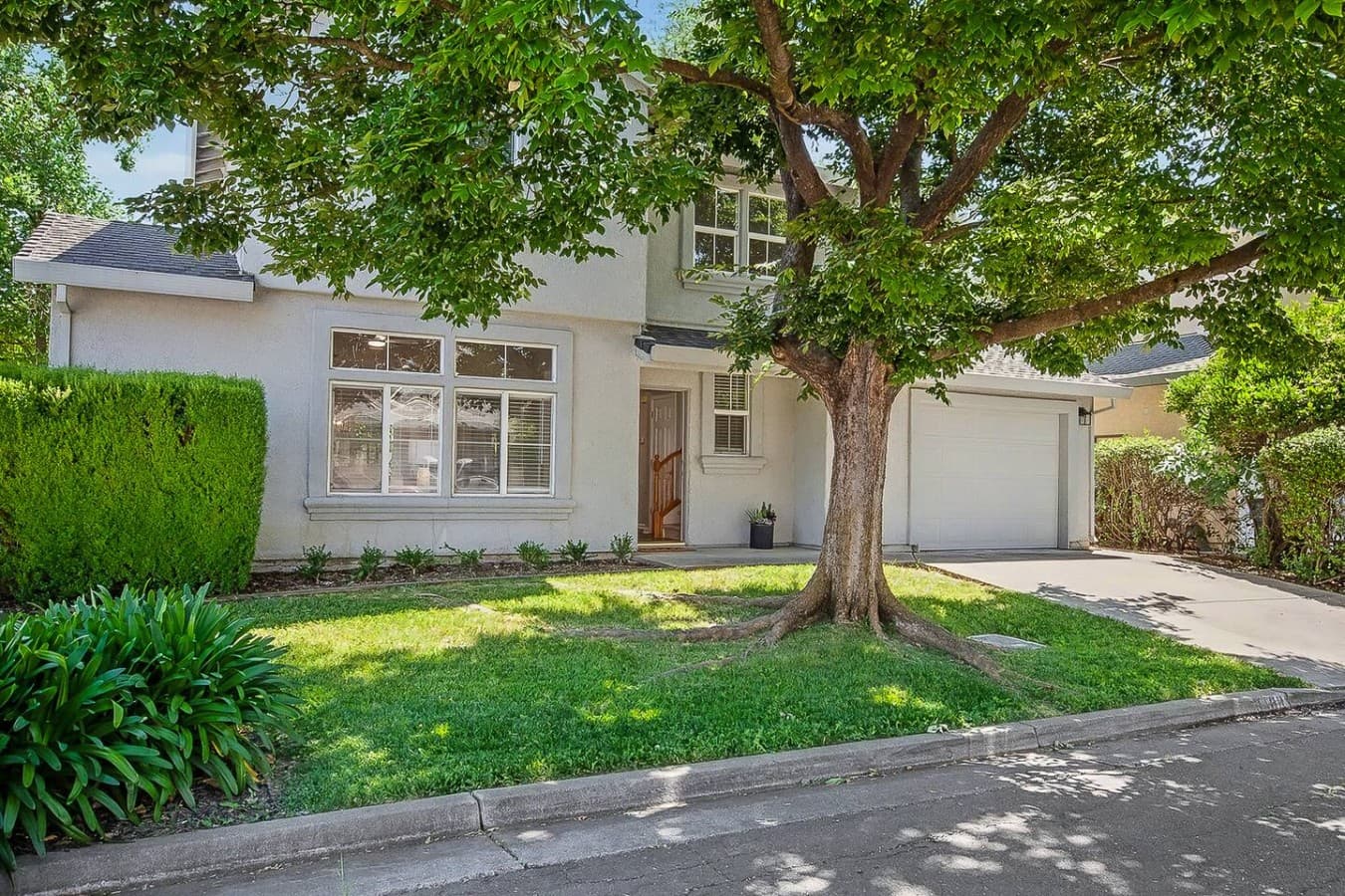 Bright townhouse exterior located on a peaceful tree lined street.