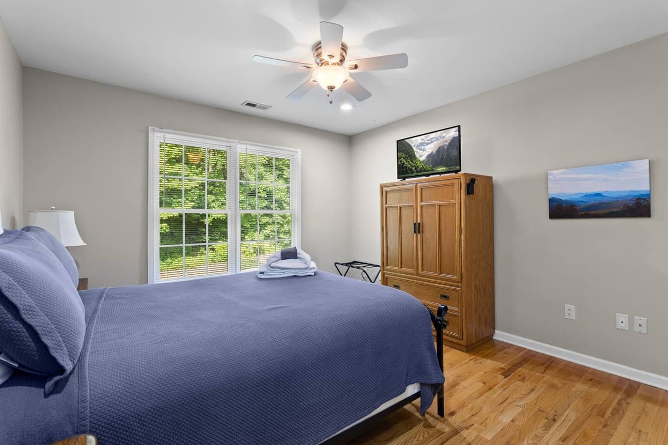 Bright bedroom retreat with large windows and relaxing wooded views.