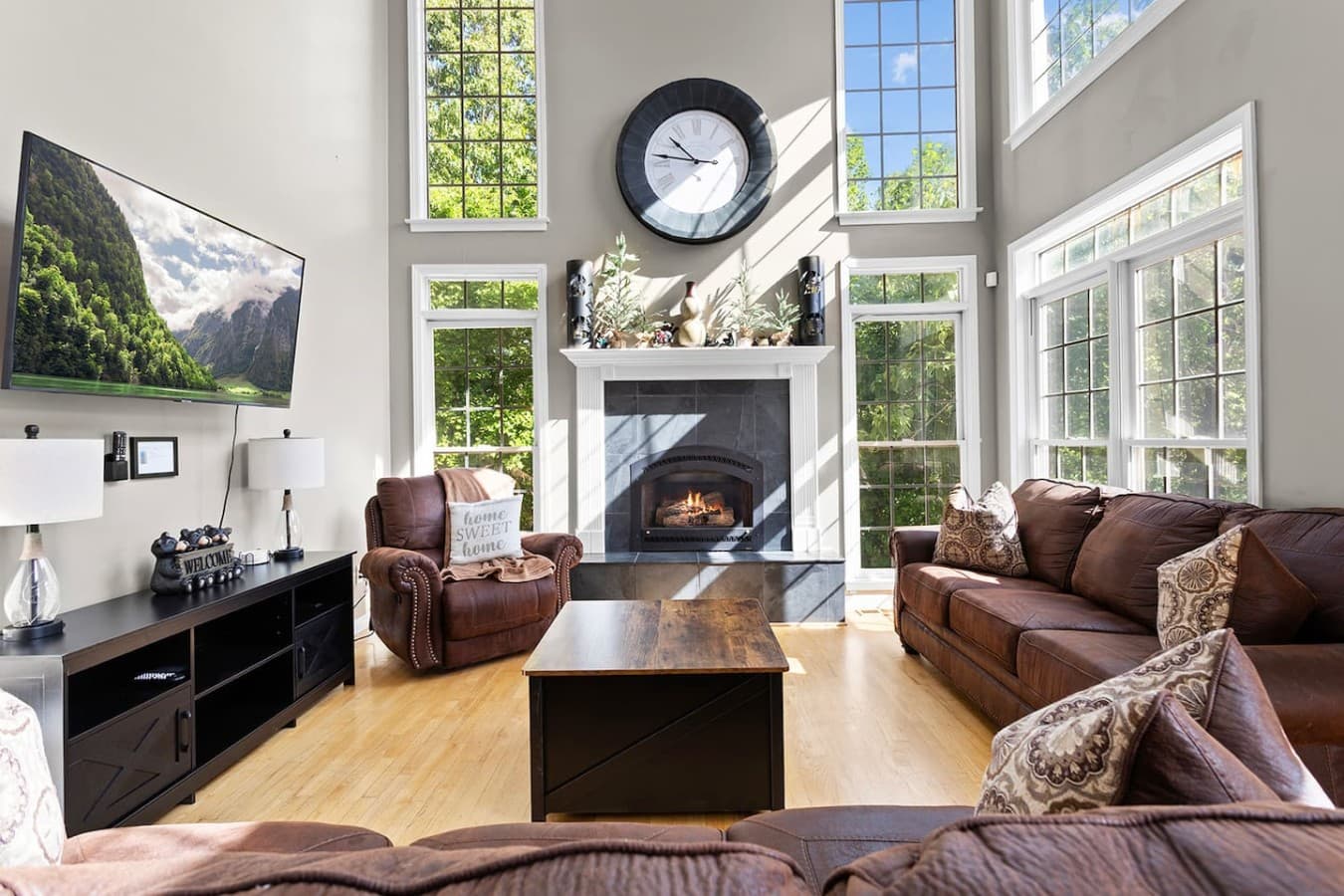 Spacious living room with tall ceilings, oversized windows, and a cozy fireplace centerpiece.