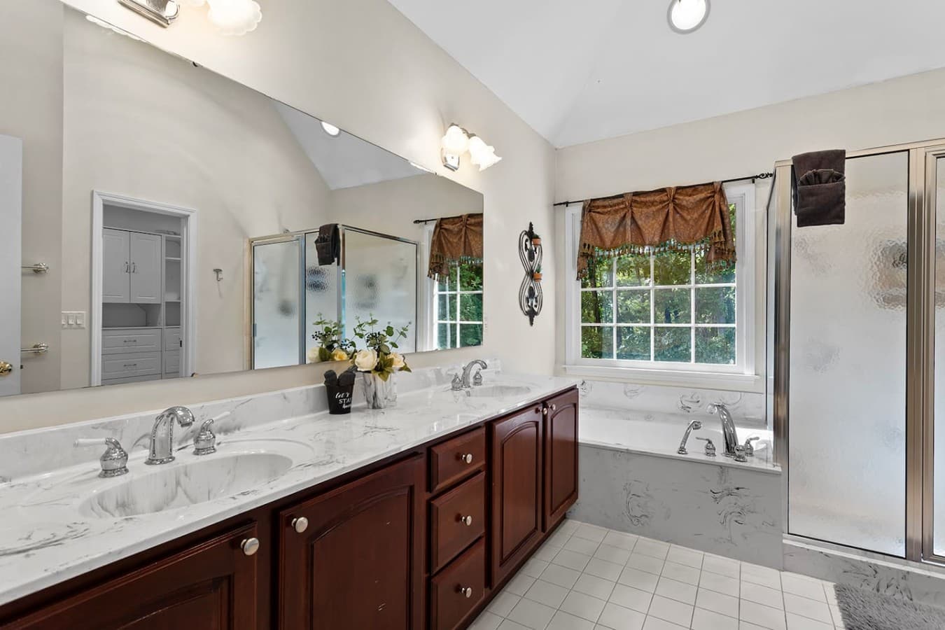 Primary bathroom with dual vanities, a soaking tub, and plenty of natural light.