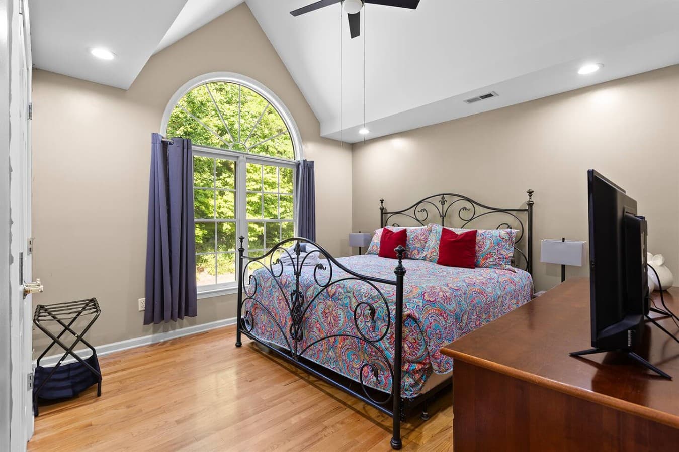 Spacious bedroom with vaulted ceilings and large windows overlooking the trees.