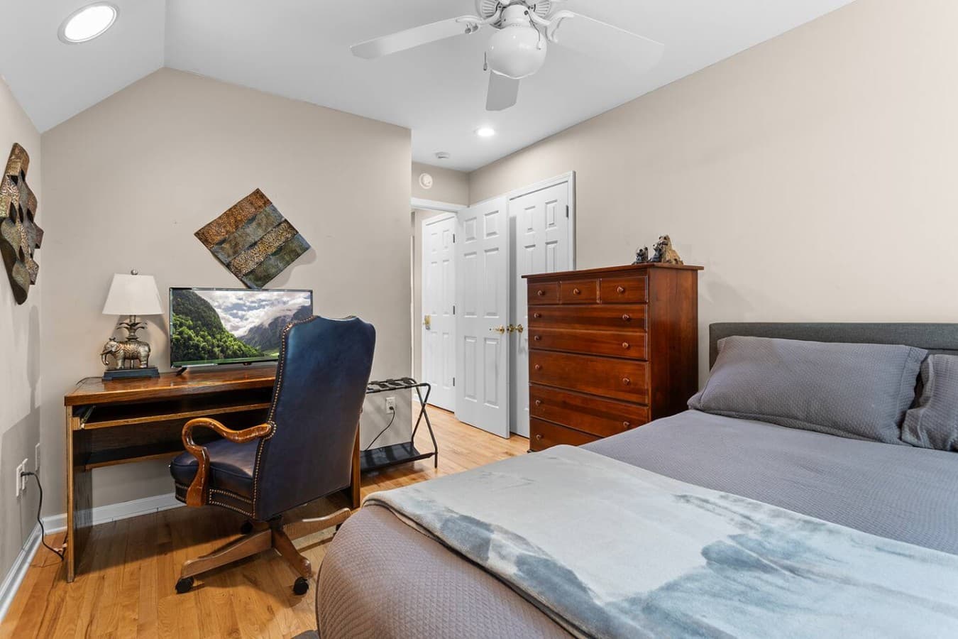 Cozy guest bedroom with warm wood accents and convenient desk space.