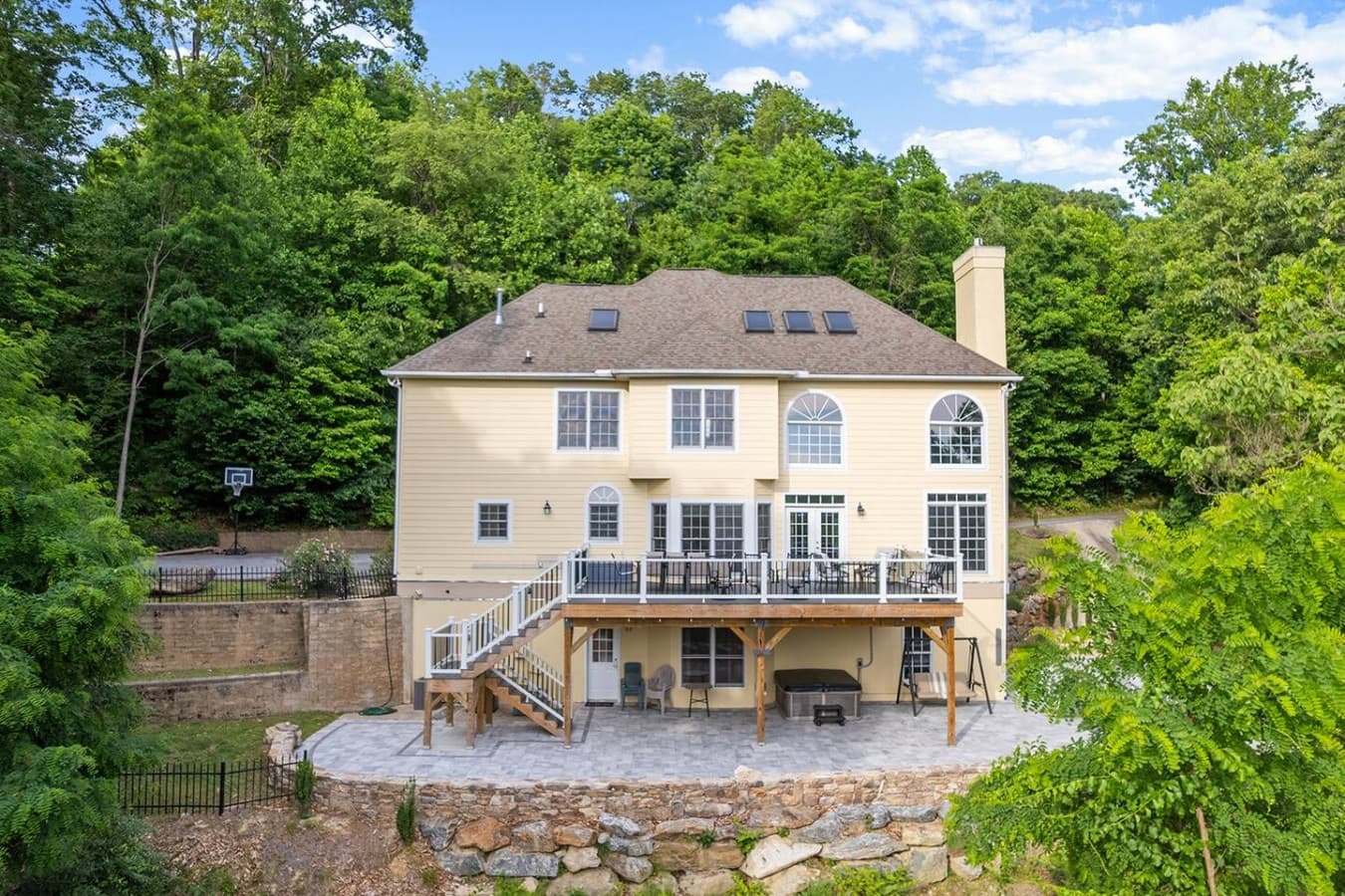 Rear exterior showcasing multiple outdoor gathering spaces and wooded privacy.