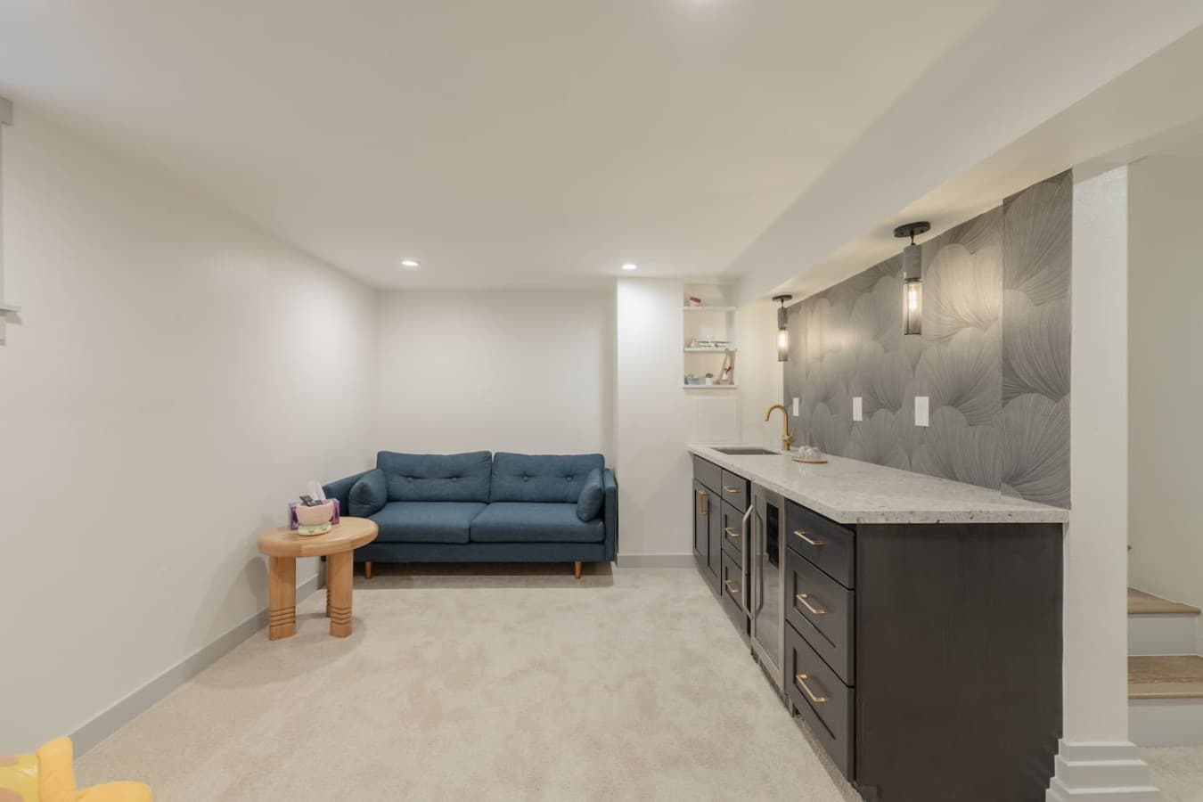 Modern downstairs wet bar with mini fridge, spacious counters, and a cozy lounge area for gathering together.