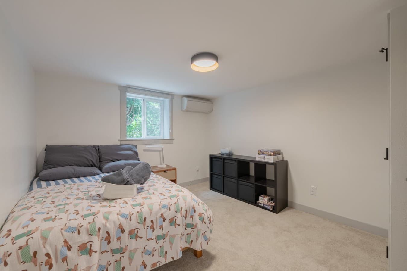 Simple and comfortable bedroom with soft carpeting, natural light, and a relaxing atmosphere for restful stays.