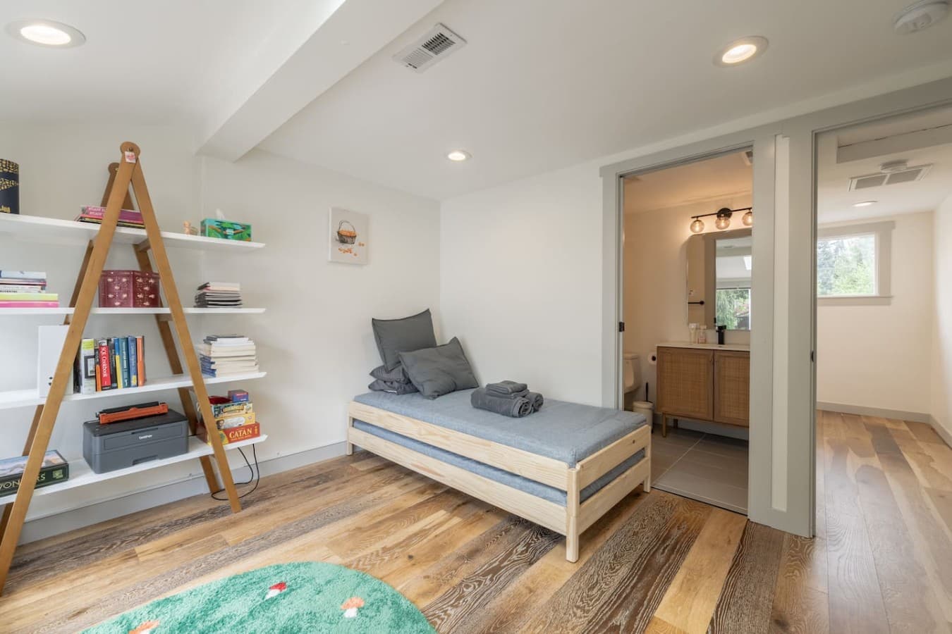 Minimalist bedroom design featuring warm wood floors, soft lighting, and convenient access to the nearby bathroom.