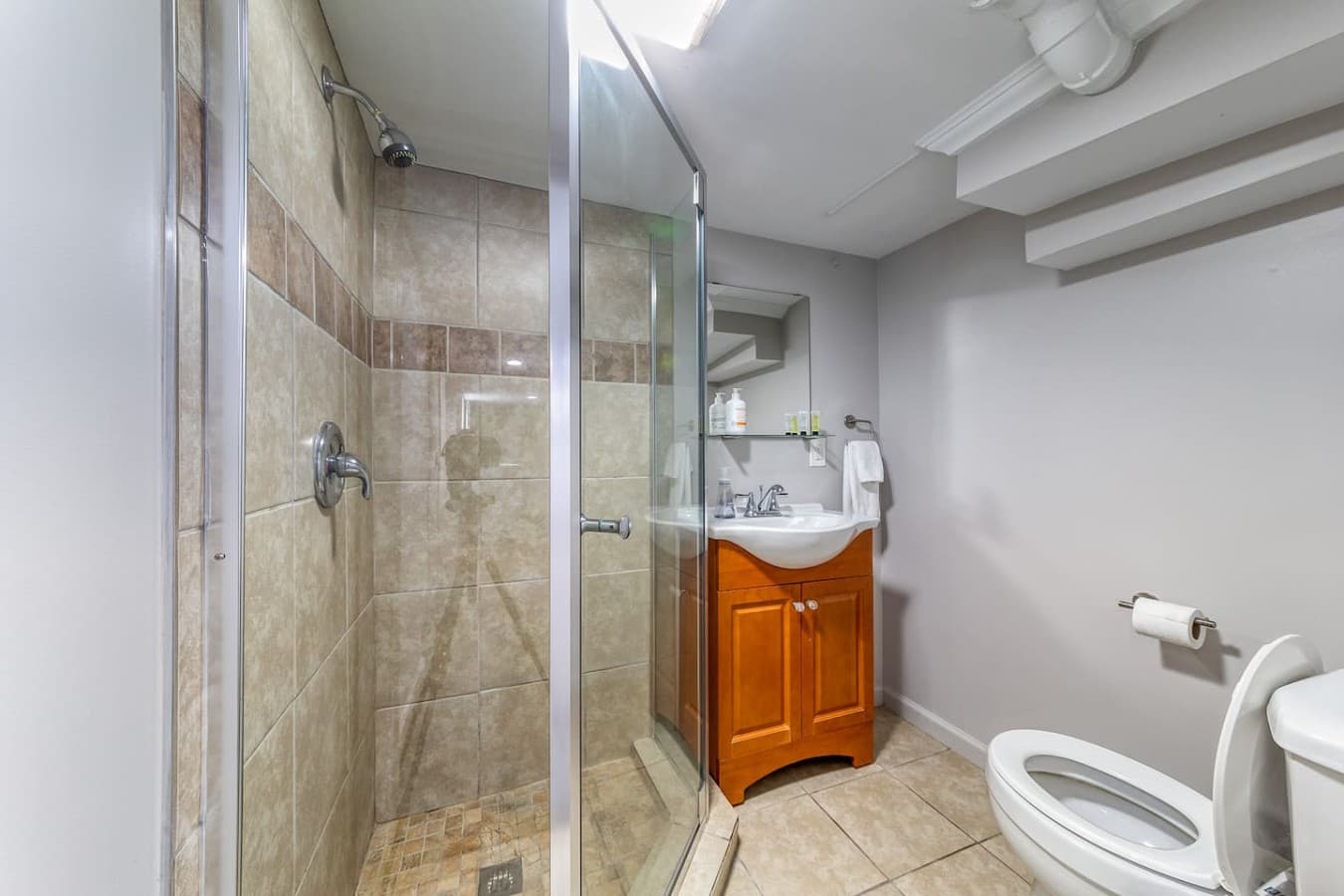Full bathroom with a walk-in glass shower and convenient vanity storage.