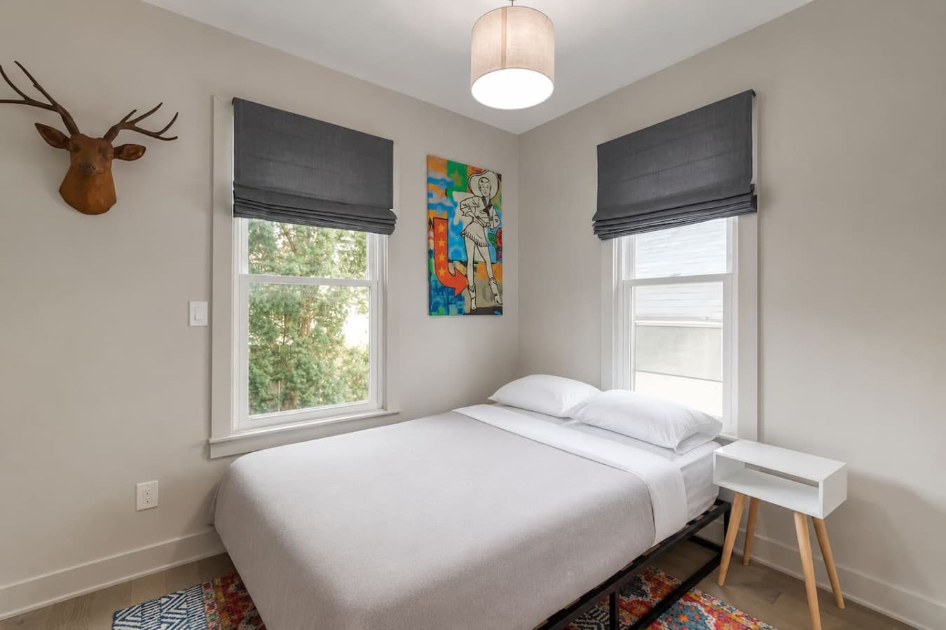 Bright and cozy bedroom with natural light and colorful artwork accents.