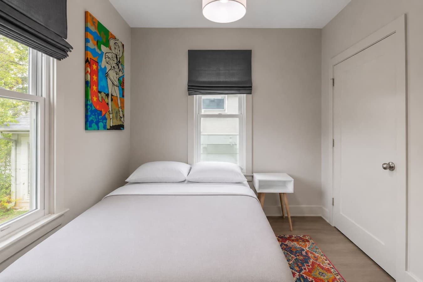 Inviting bedroom with soft bedding, blackout shades, and vibrant artwork touches.
