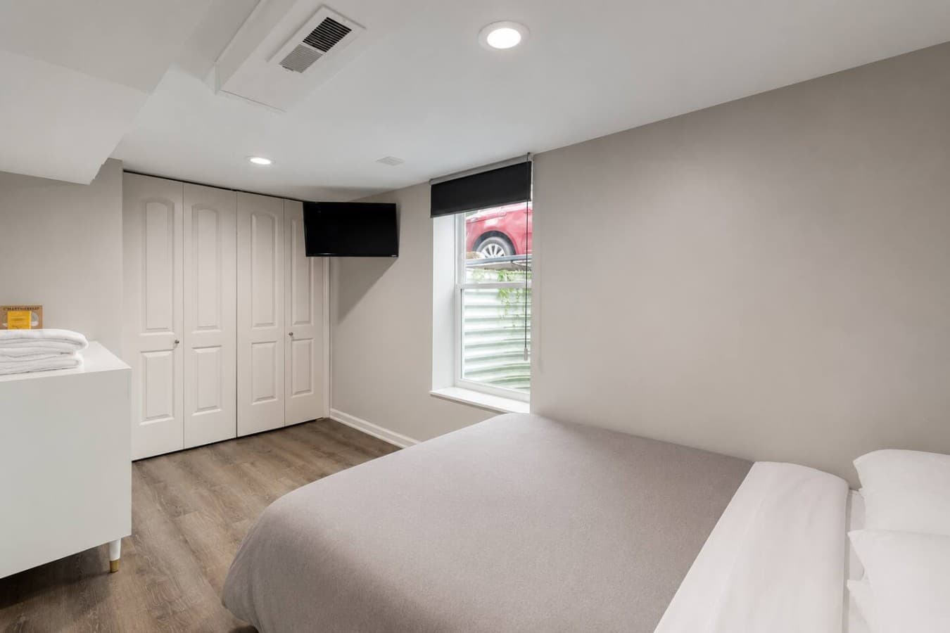 Minimalist bedroom with a comfortable bed, smart TV, and blackout shades for restful nights.