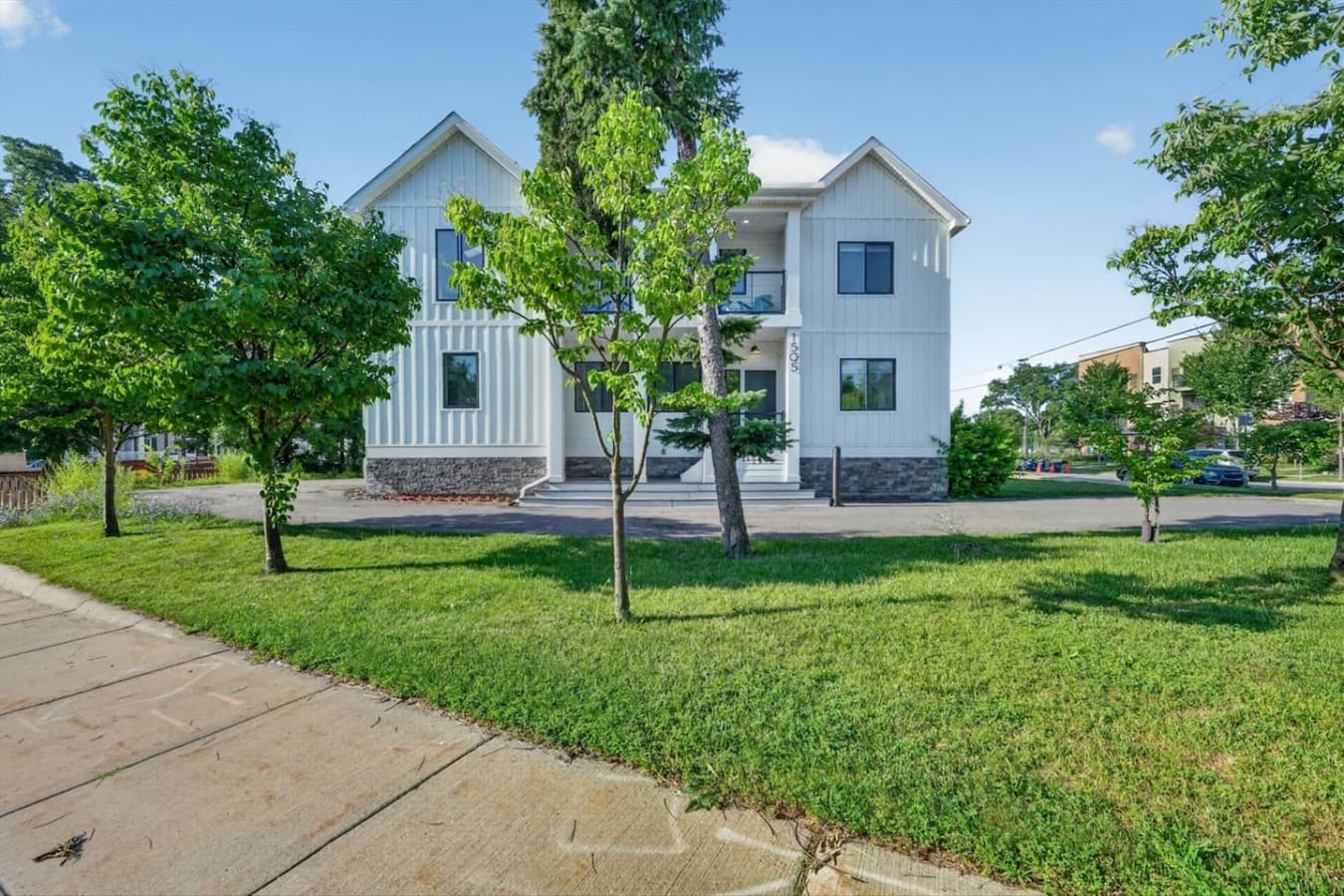 Bright, modern façade surrounded by mature trees and a spacious lawn.