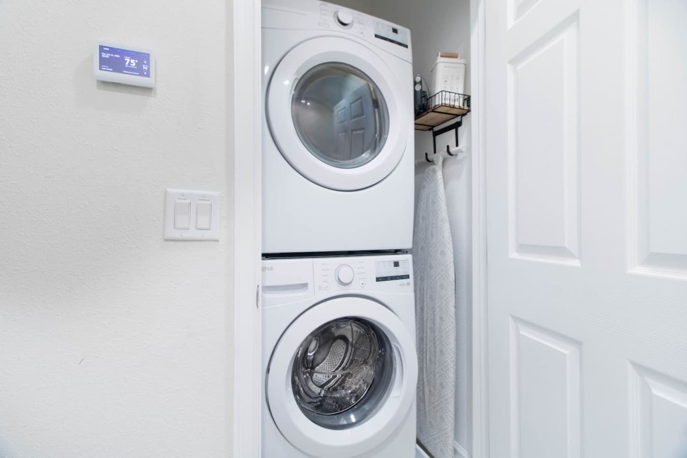 Convenient in home laundry closet featuring a stacked washer and dryer with additional storage space.