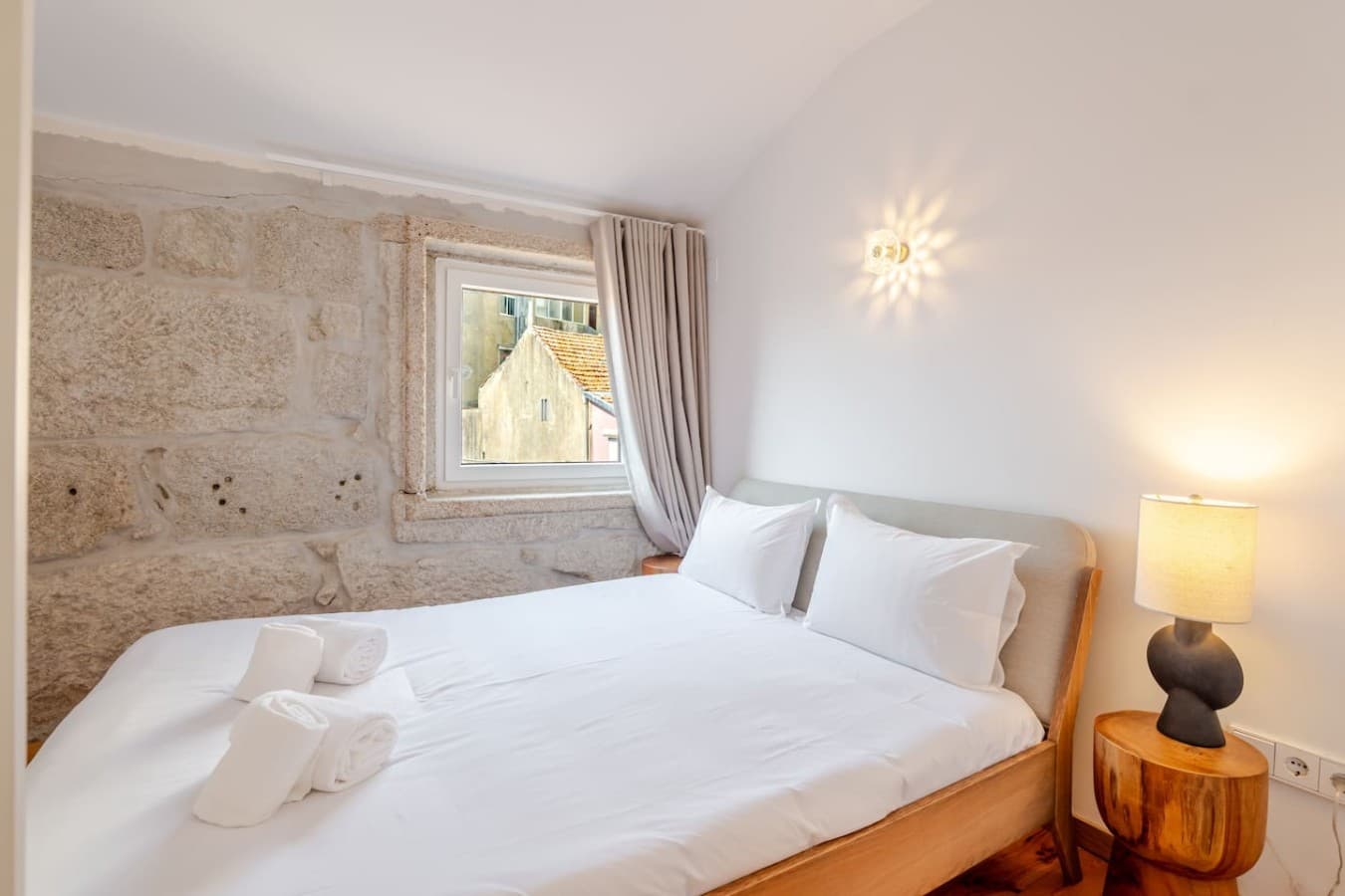 Relax in a serene bedroom featuring original stone details, soft natural light and a king size bed.