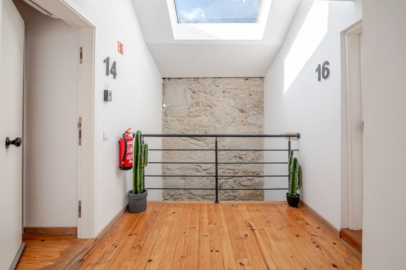 Spacious exterior landing featuring skylights, stone accent walls, and clean shared access to the apartments.