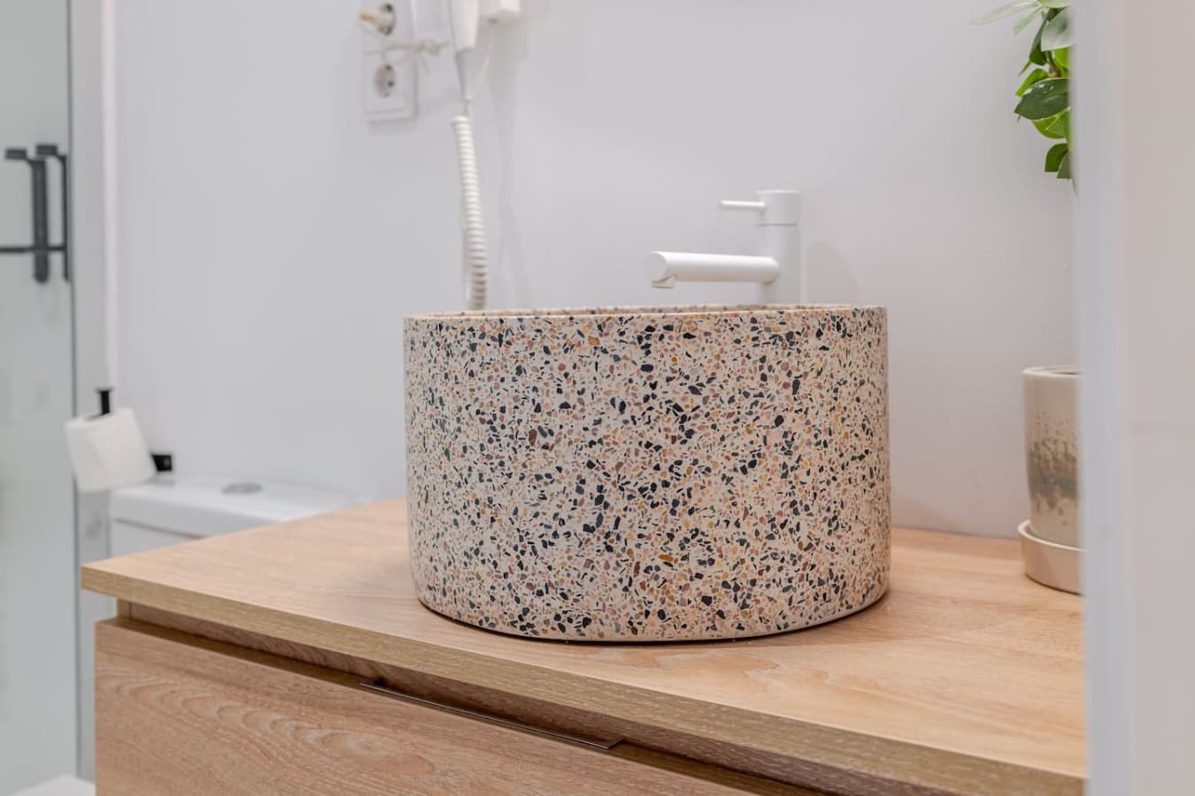 Beautifully designed bathroom vanity with a distinctive terrazzo vessel sink and natural wood countertop.