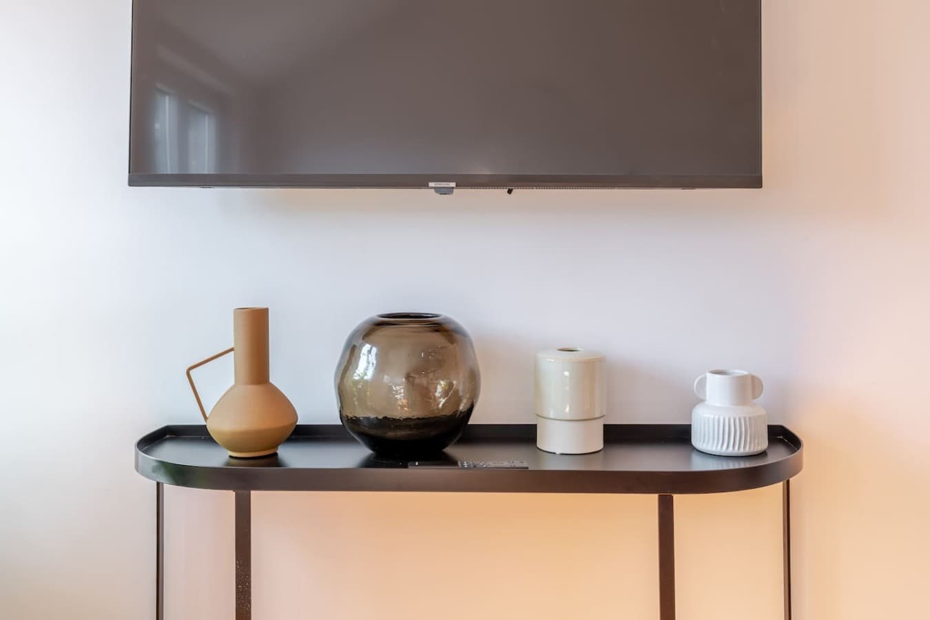 Wall-mounted TV complemented by a stylish console table with carefully curated decorative accents.