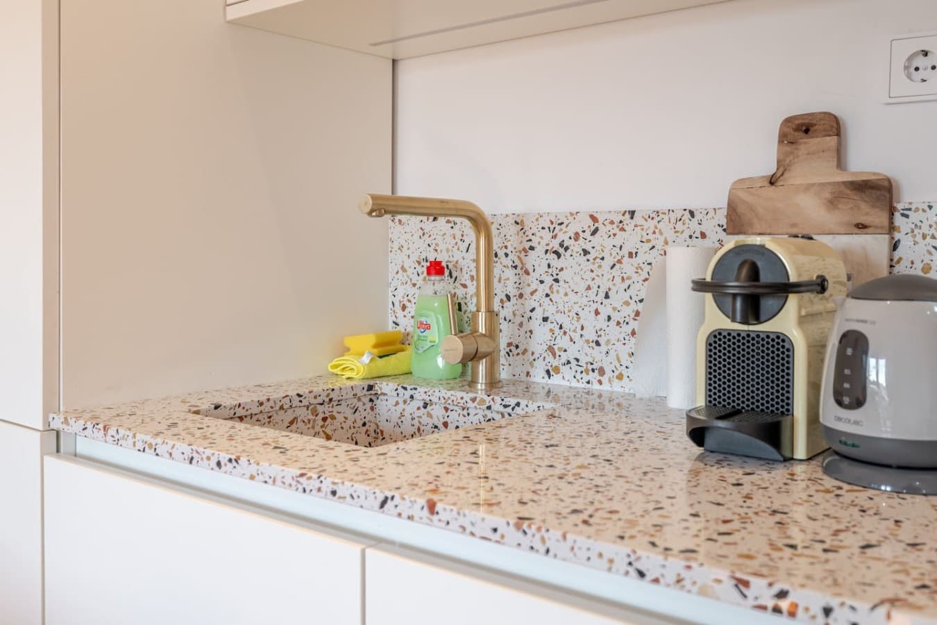 A stylish kitchen corner equipped with premium finishes, a coffee machine, kettle, and ample countertop space for meal preparation.
