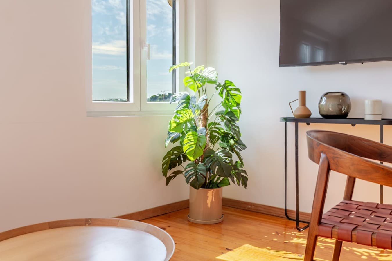 Relax in the sun-filled living area with a Smart TV and lush greenery for a cozy, inviting atmosphere.