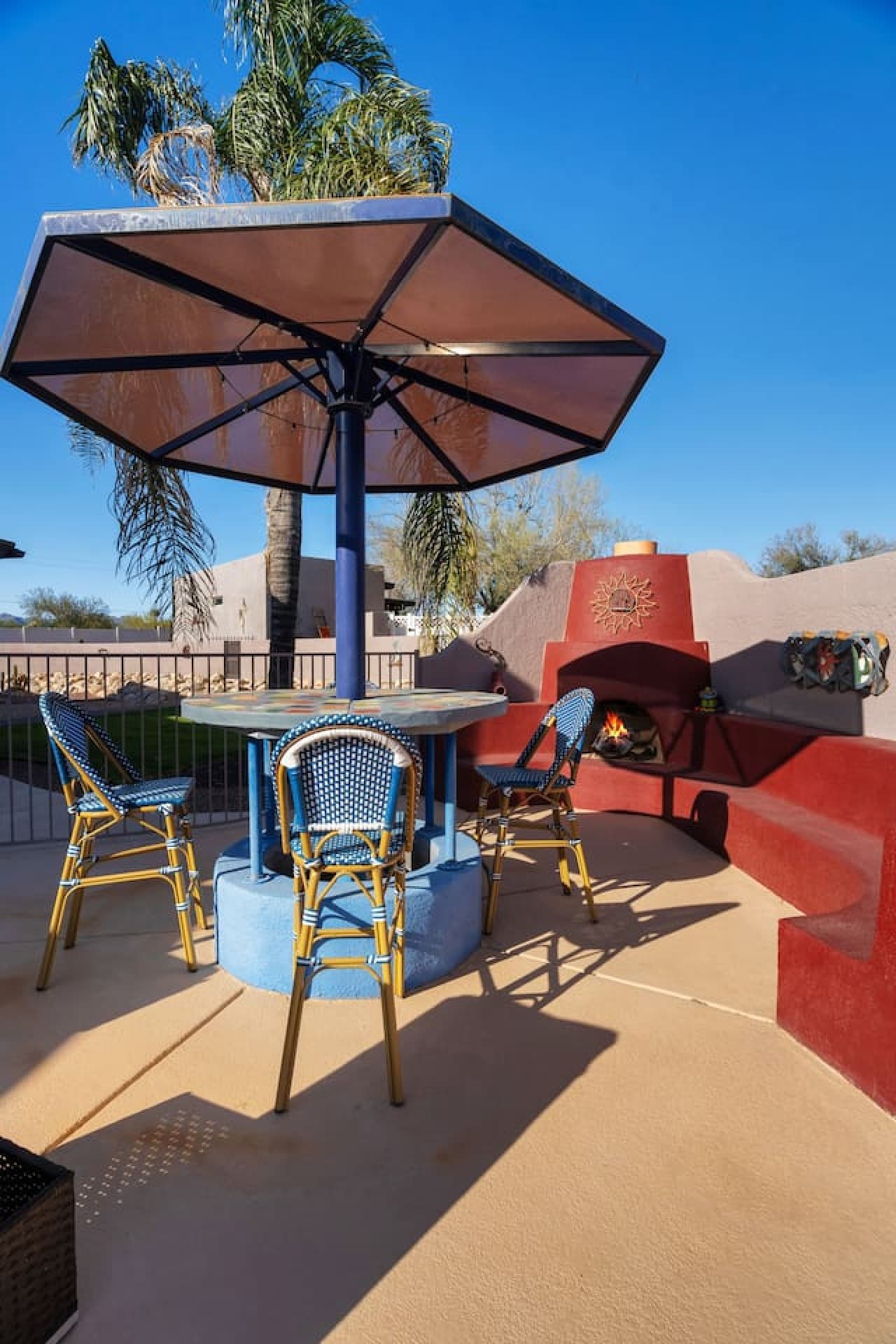 Outdoor dining area with umbrella seating and built in fireplace.