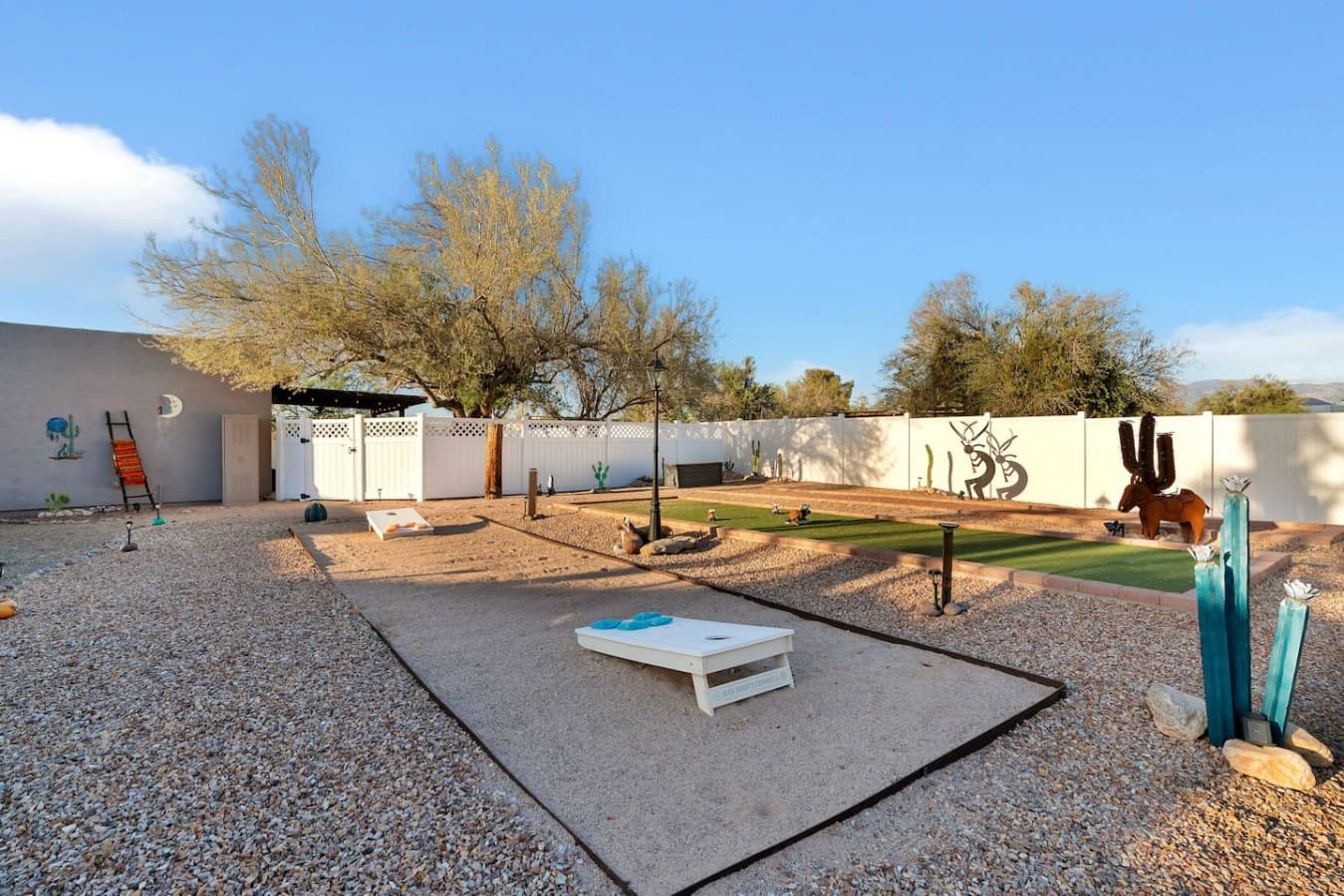 Outdoor game space with cornhole and open yard for fun.