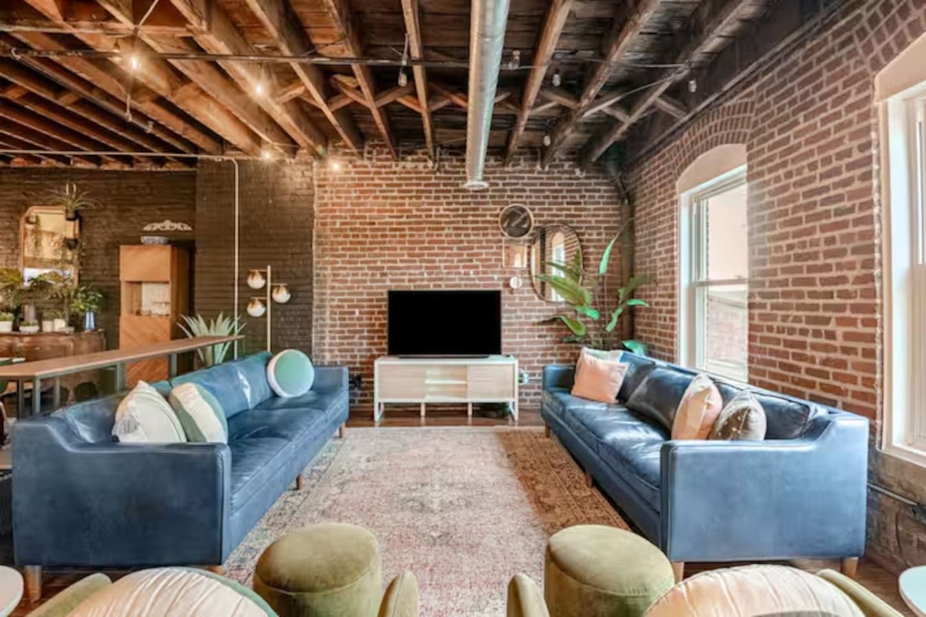 Comfortable lounge area with large TV and exposed brick walls.