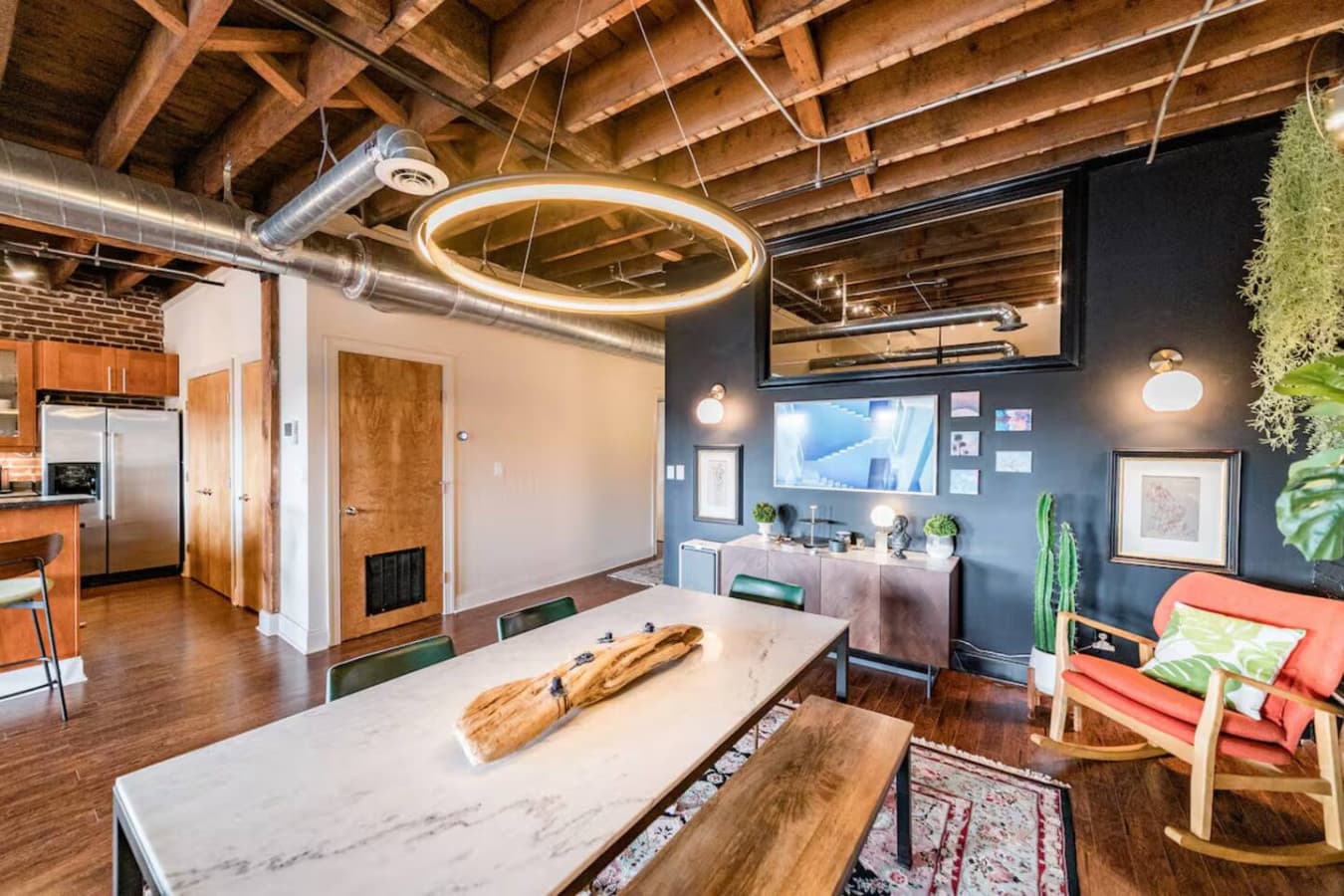 Long dining table beneath modern ring lighting.