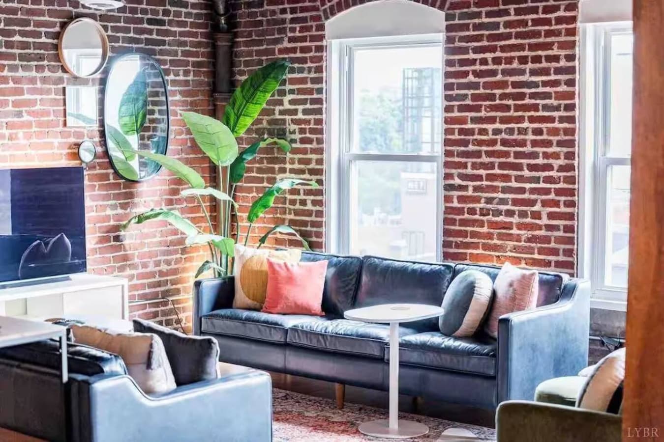 Cozy sofa seating framed by exposed brick and greenery.