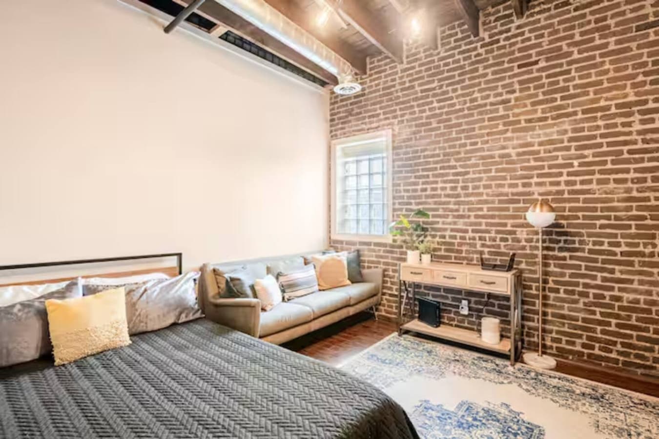 Spacious bedroom with exposed brick and cozy seating area.