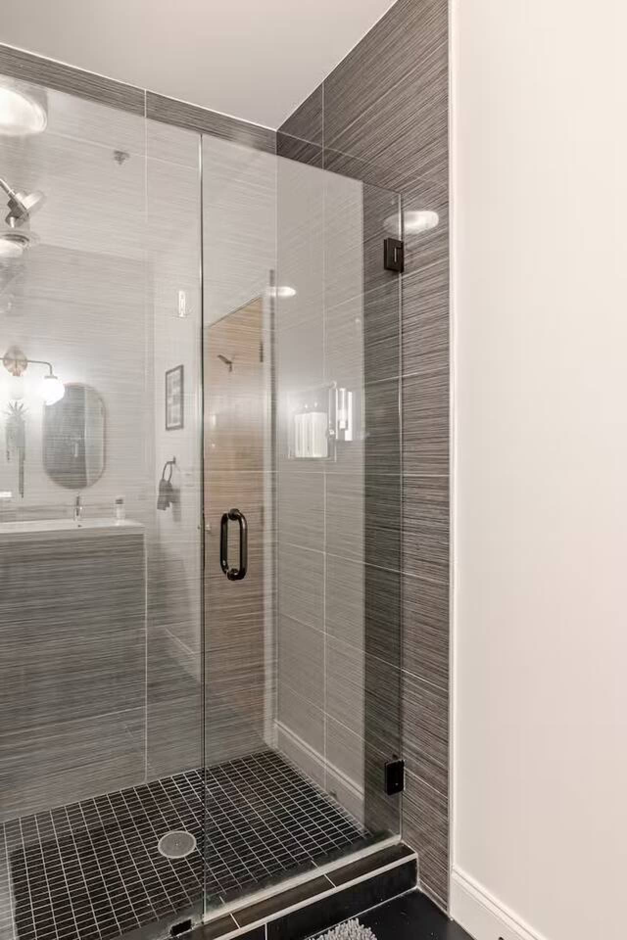 Glass enclosed shower with sleek tile design.