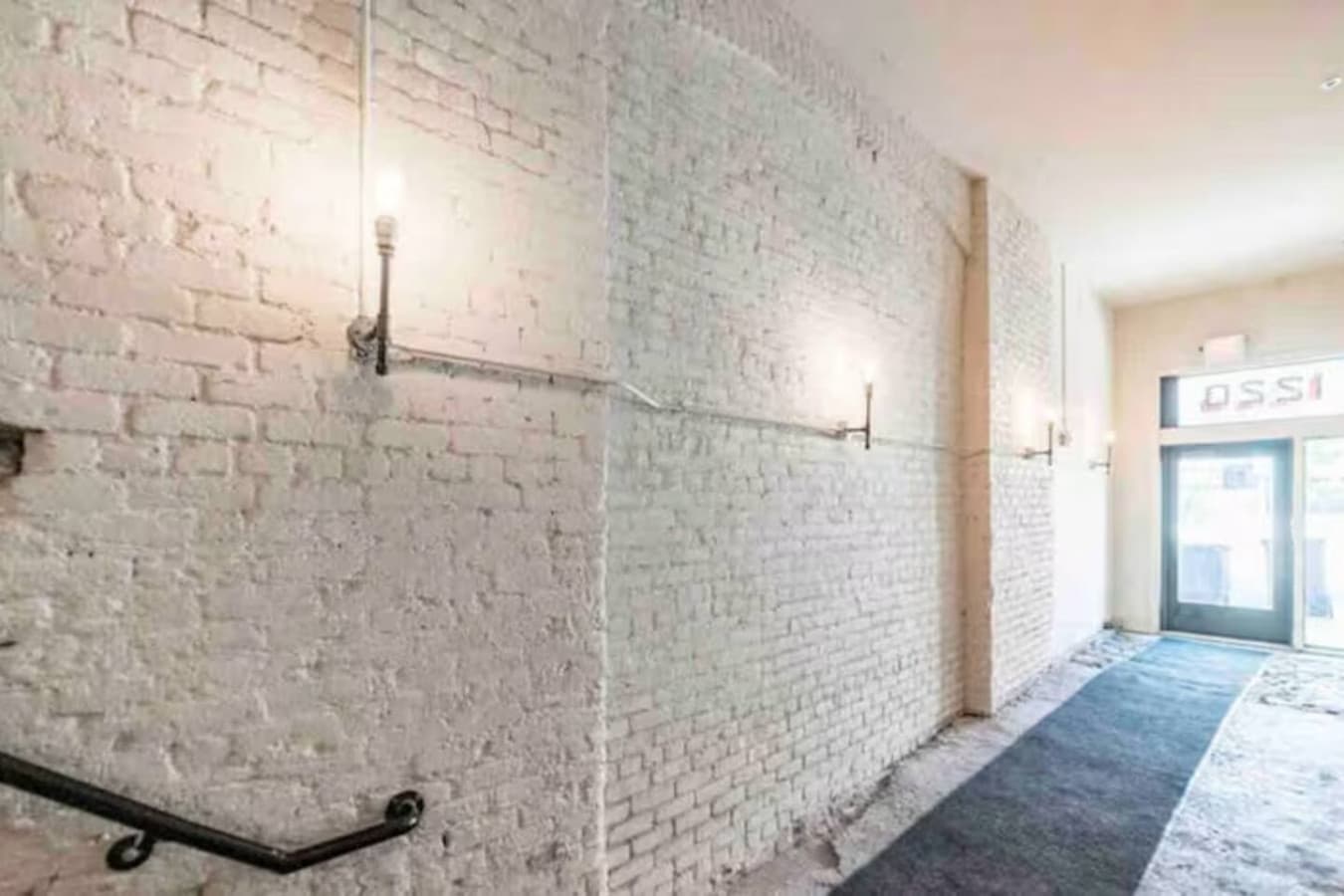 Hallway with exposed brick and industrial wall lighting.