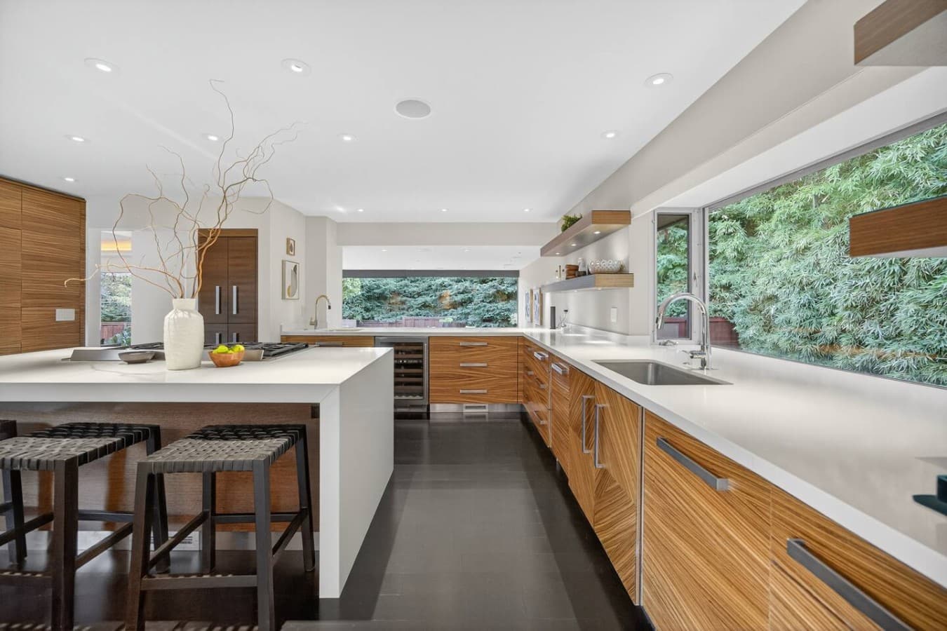 Sun filled culinary space with abundant storage, modern finishes, and picturesque garden views.