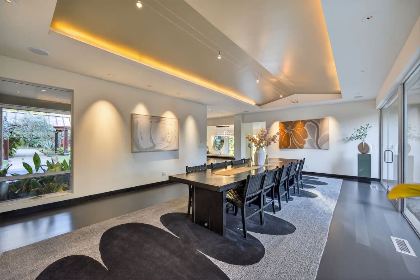 Sophisticated entertaining space featuring a custom dining table, gallery style lighting, and elegant contemporary design.