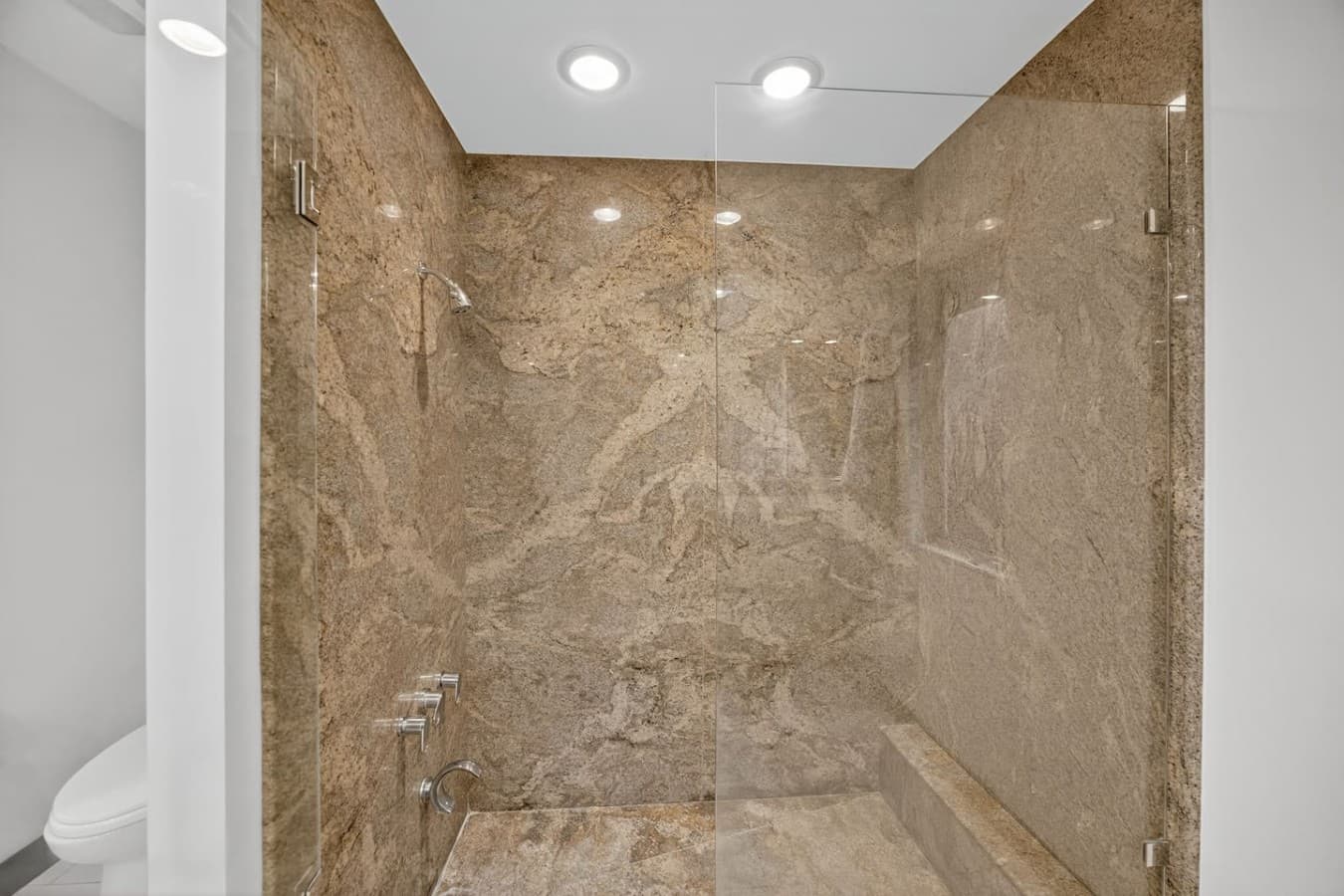 Luxurious walk in shower featuring floor to ceiling stone tile and a spa inspired design.