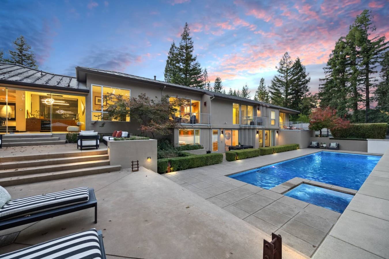 Luxury outdoor oasis featuring a sparkling pool, multiple lounge areas, and a serene tree lined setting.