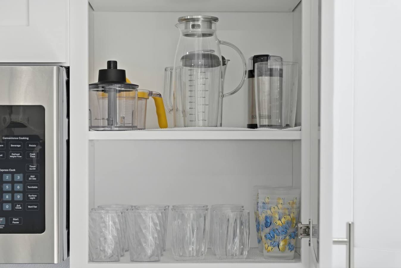 Stocked cabinets with glassware and kitchen essentials.