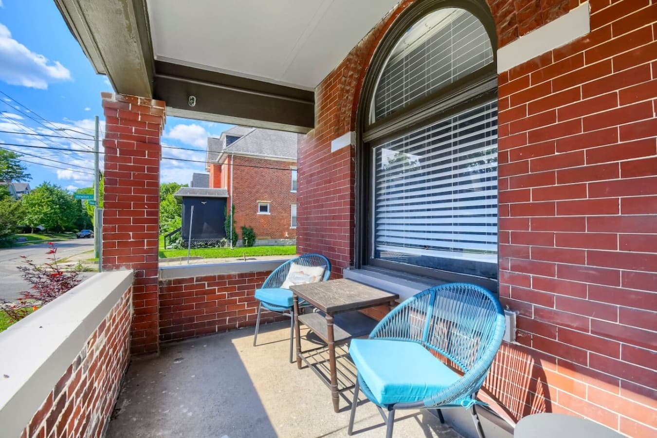 Relax on the covered porch with outdoor seating and enjoy the neighborhood atmosphere.